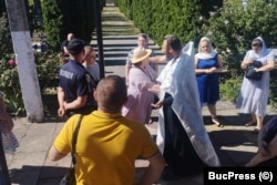 Preotul Cristofor Gabor, alături de credincioși și un polițist ucrainean, în timpul slujbei din 25 august.