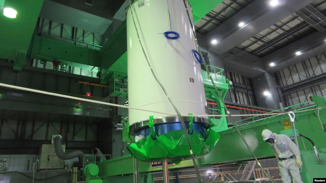 A cask of nuclear fuel is lifted and moved by workers during operations to remove fuel rods from a spent fuel pool inside the No.4 reactor building at Tokyo Electric Power Co's (TEPCO) Fukushima Daiichi nuclear power plant on November 18.