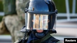 Belarusyň kanun goraýjy işgäri prezident saýlawlarynyň netijelerine garşy Minskde geçirilen oppozisiýa demonstrasiýasyna seredýär. 22-nji awgust, 2020 ý.