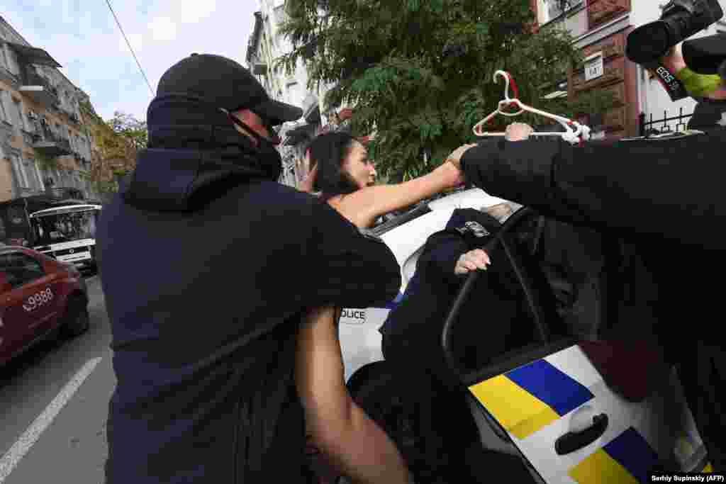 Police officers detain a naked FEMEN activist during a protest at the Polish Embassy in Kyiv against Poland&#39;s new, more restrictive abortion laws. (AFP/Sergei Supinsky)