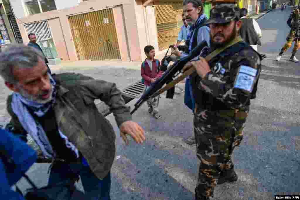 A member of the Taliban pushes a journalist who was covering a demonstration by women protesters outside a school in Kabul.