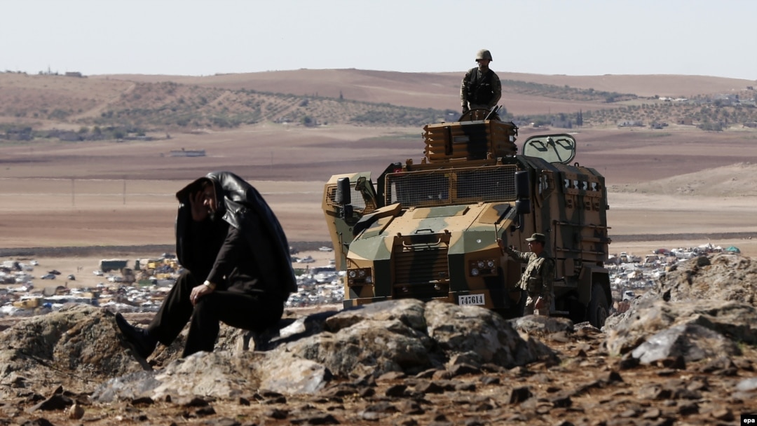 Turkish soldiers on duty as a man watches from a hill in Turkish territory during fighting between Syrian Kurdish fighters and Islamic State militants.