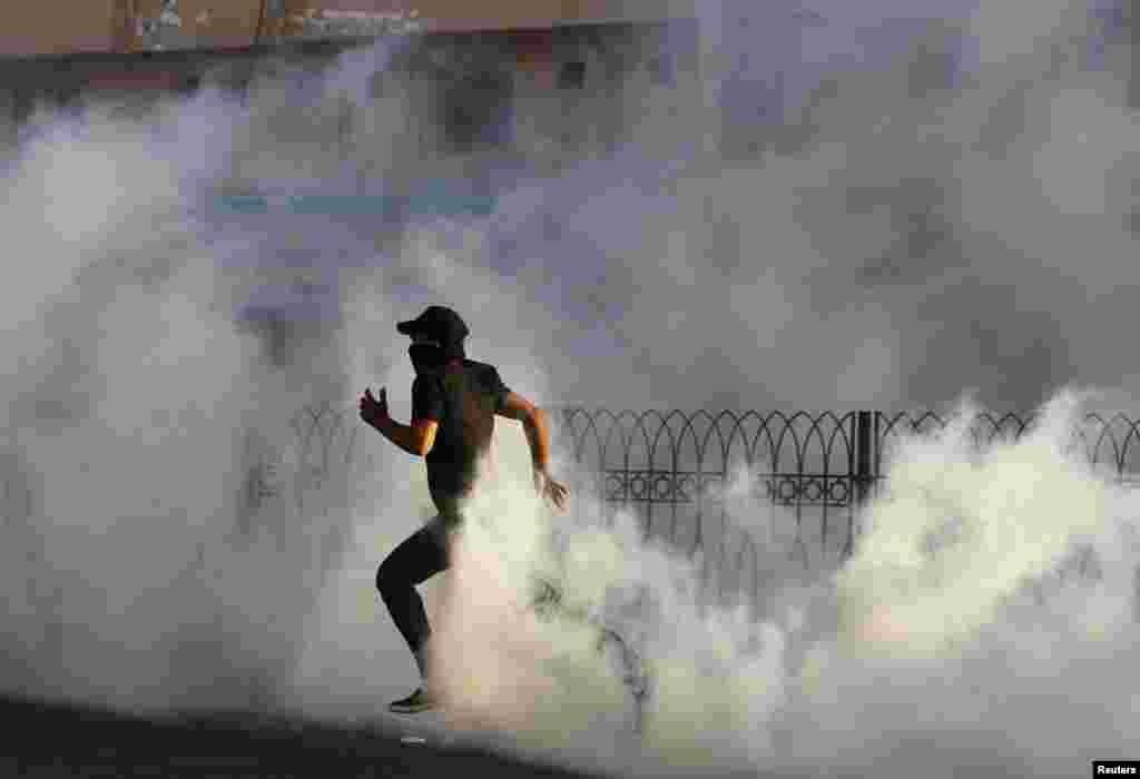 A protester runs through a cloud of tear gas fired by Bahraini riot police during a protest in the village of Sitra, south of Manama. REUTERS/Hamad I Mohammed