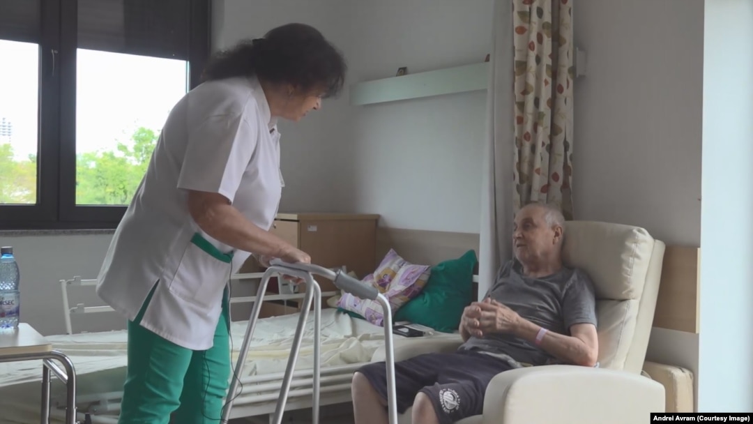 Unul dintre saloanele centrului pentru tratamente paliative Hospice Casa Speranței. Asistenta-șefă discută cu un pacient care urmează să fie externat. 