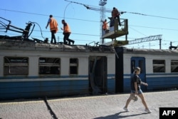 Lucrători feroviari și o trecătoare la gara din Lozova, după atacul rusesc din 5 august, 2025.
