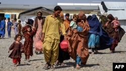 Afghan returnees carrying their belongings arrive from Pakistan at a registration center in the Takhta Pul district of Afghanistan's Kandahar Province. According to the United Nations, more than 2.6 million Afghans have returned home from Pakistan since a mass expulsion campaign began in 2023.