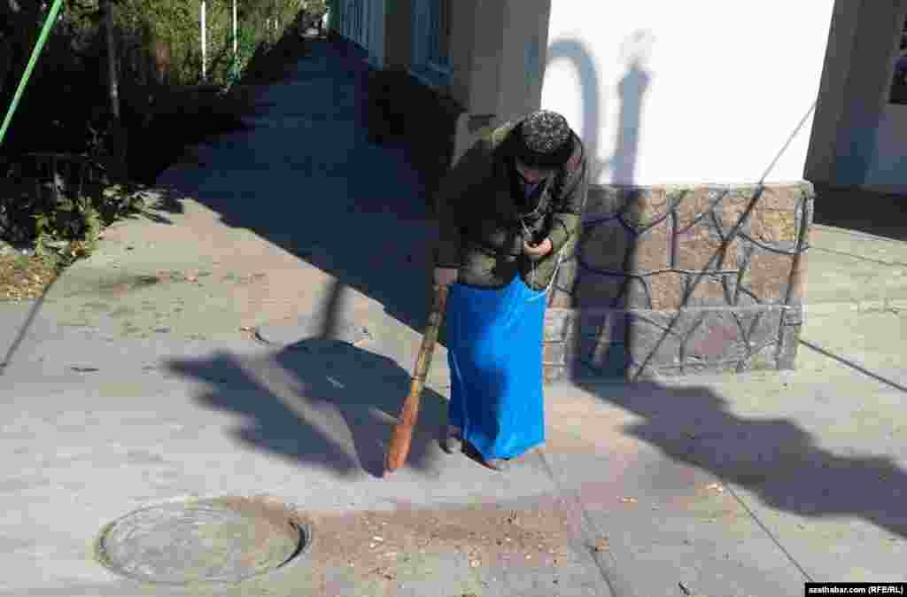 Bir ýaş gyz köçe süpürýär