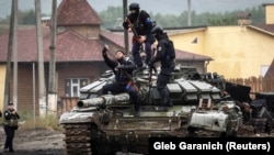 Ushtarët ukrainas fotografhen në një tank të shkatërruar rus në Izjum, qytet që së fundmi është çliruar nga forcat e Kievit. 14 shtator 2022.