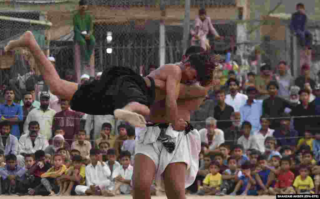 Wrestlers in action during a traditional Sindhi Malakhra wrestling event in Karachi, Pakistan. During a Malakhra match, both wrestlers tie twisted cloth around their opponents&#39; waists. They then grab the opponent&#39;s waist cloth and attempt to throw him to the ground.