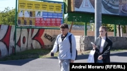 Tineri trecând pe lângă afișaj electoral în Chișinău, 19 septembrie 2025