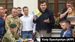 Mikheil Saakashvili speaks to the media while Ukrainian border guards try to hand him a protocol of administrative offense near the hotel where he is staying in the western city of Lviv on September 12.
