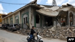 Юнак проїжджає на мопеді повз мечеть, яка постраждала внаслідок нещодавнього ізраїльського удару в південно-ліванському селі Кфар-Сір, 21 квітня 2026 року 