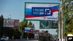 Harci jármű halad el egy óriásplakát alatt, amelyen az áll: „Oroszországgal örökké, szeptember 27.” Luhanszk, 2022. szeptember 22.