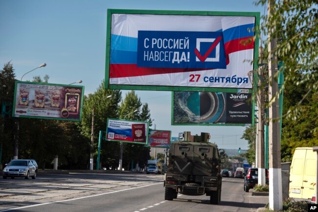 Rusko vojno vozilo prolazi pored plakata sa porukom "Sa Rusijom zauvijek, 27. septembar", u Lugansku, Ukrajina, 22. septembar 2022.