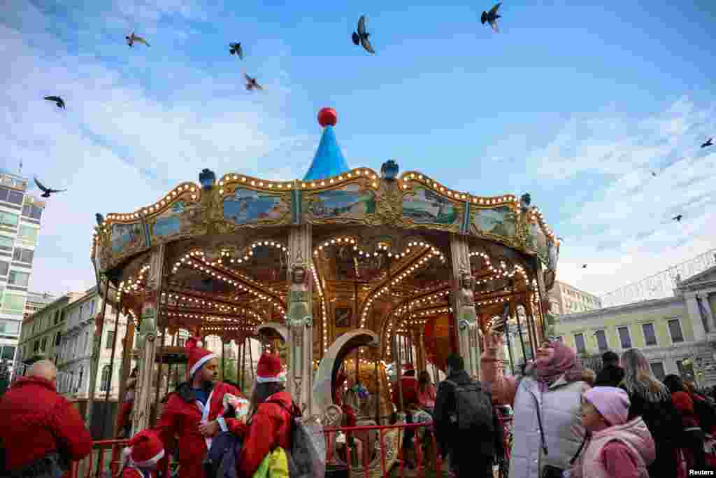 Oamenii se adună în jurul unui carusel la târgul de Crăciun din Atena, Grecia, în perioada sărbătorilor de iarnă, pe 21 decembrie 2025.