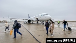 Пассажиры идут по взлетно-посадочной полосе аэропорта в Уральске. 26 октября 2020 года.