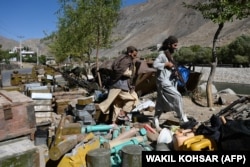 Taliban fighters walk past ammunition along a road in the Bazark district of Panjshir Province in September 2021.