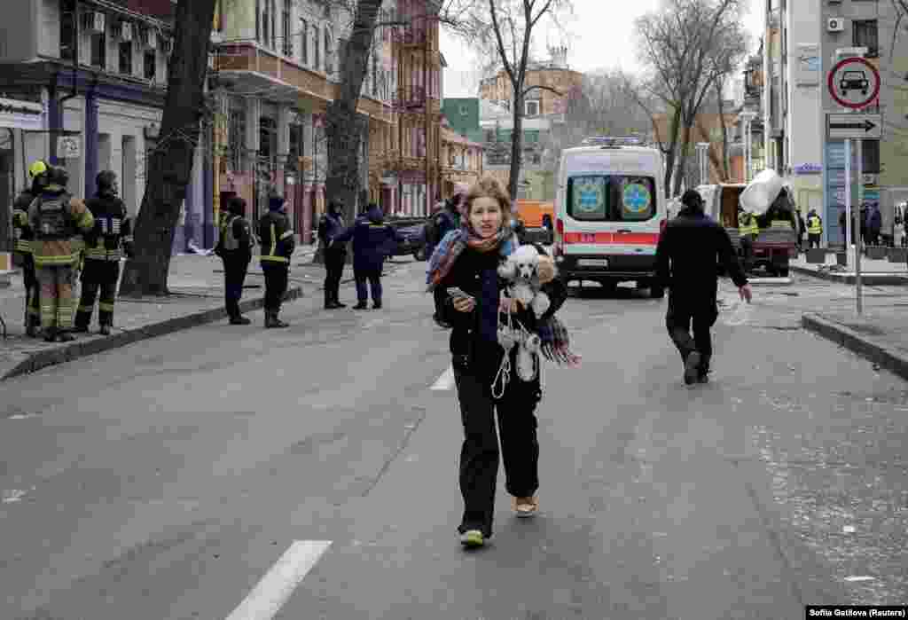 A woman walks with her dog away from apartment buildings that were hit by a Russian missile strike on the Ukrainian city of Kharkiv.&nbsp;