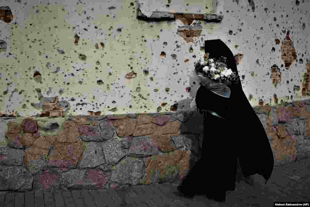 Монахиня проходит мимо пострадавшей от снаряда Украинской православной церкви (МП) по пути на пасхальную службу в Иверский монастырь под Донецком