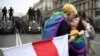 Protesters with rainbow-themed flags embrace near barriers erected by Belarusian police during an opposition rally against police brutality and the presidential election results in Minsk on September 6, 2020.