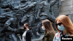 چند شهروند اوکراینی، ماسک بر صورت، در حال بازدید از موزه جنگ جهانی دوم؛ شنبه ۲۰ اردیبهشت