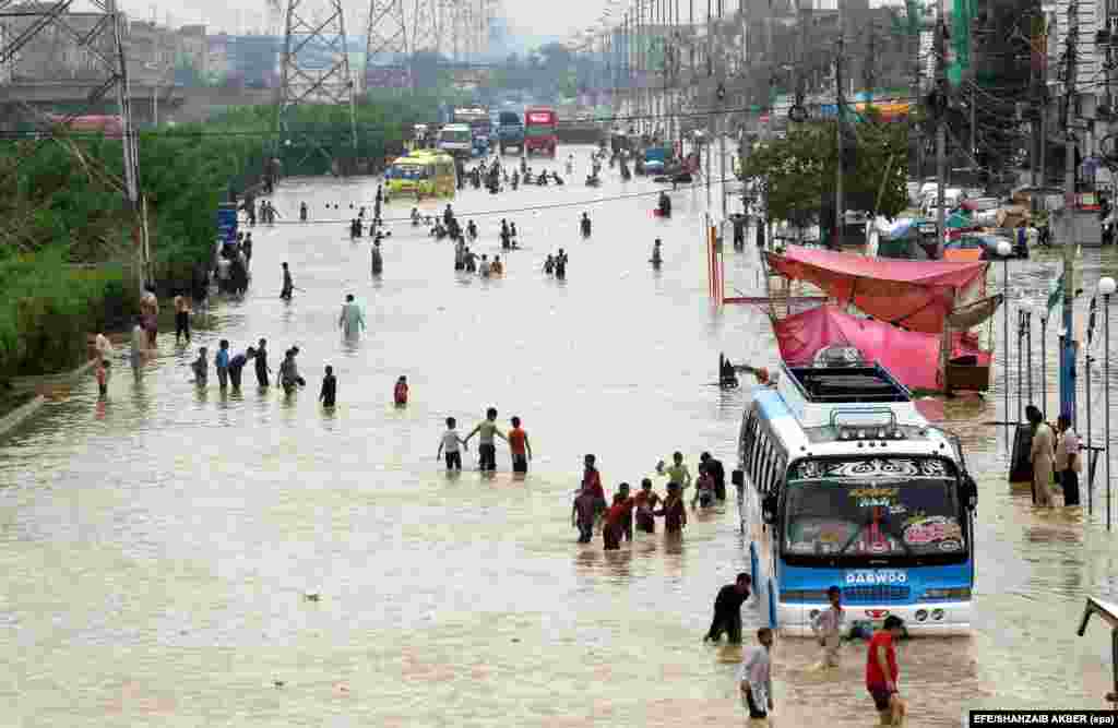 People make their way on an flooded street after a heavy downpour in Karachi, Pakistan. Massive flooding is blamed for the deaths of at least 2,100 people in the region. (epa/Shahzaib Akber)