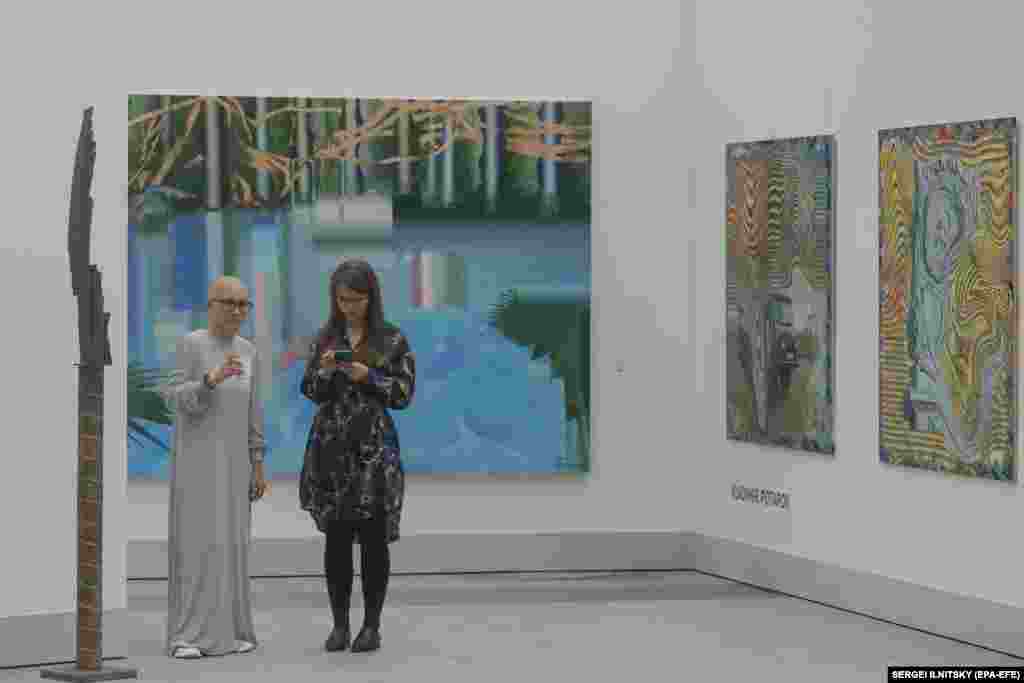 Visitors stand near artworks by Russia&#39;s Vladimir Potapov.