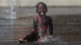 EUROPE -- A child plays with water in a fountain during a hot summer day in Brussels, July 24, 2019