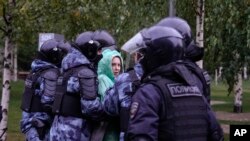 Орусияда митингге чыккан кызды полиция кызматкерлери кармап баратышат. 