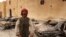 A man stands in front of burnt vehicles outside a state security building in Tobruk, east of Libya.