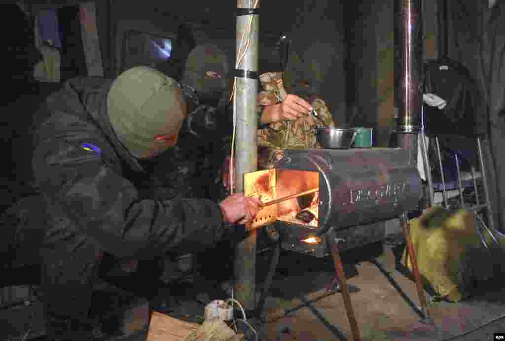 Ukrainian servicemen warm themselves in a tent with a moveable wood stove, given to them by volunteers, at a checkpoint near Mariupol, Ukraine. (epa/Photomig) 