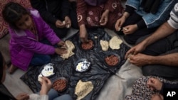 Anëtarët e familjes Abu Jarad duke ngrënë mëngjes në një tendë të improvizuar në zonën Muasi, Gaza jugore. 1 janar 2024.