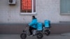 A food delivery courier rides past an exchange office screen showing the currency exchange rates of U.S. Dollar an Euro to Russian Rubles in Moscow, Russia, Friday, April 7, 2023