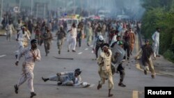 Antigovernment protesters run after police personnel during the Revolution March in Islamabad on September 1.