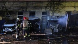 Firefighters stand near burned-out cars at an impact site after a Russian drone attack in Kyiv on November 8.