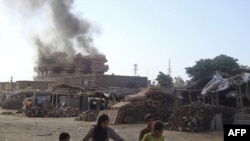 Afghan children walk along a street in Konduz as smoke rises from the site of the June 2 attack.