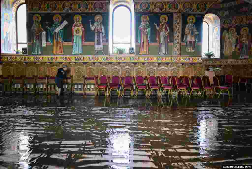 A woman cleans the floor of a church after floodwaters withdrew from the village of Pechea, Romania.