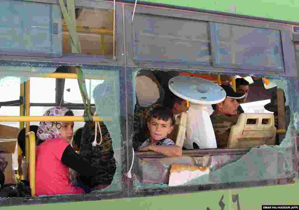 Evacuated Syrians from Fuaa and Kafraya towns in Idlib Province are seen through a broken bus window. Several thousand residents evacuated the two pro-regime towns in northern Syria, putting an end to one of the longest sieges of the country&#39;s seven-year civil war. Fuaa and Kafraya are the last remaining areas under blockade in Syria and a rare example of pro-government towns surrounded by rebel forces. (AFP/Omar Haj Kadour)