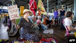 Protestatari din mișcarea Extinction Rebellion (XR) protestând la aeroportul Schiphol din Amsterdam, sâmbătă, 27 iulie. Ceva mai devreme, colegii lor din Paris fuseseră opriți de poliție să protesteze la Podul Artelor din capitala franceză. 