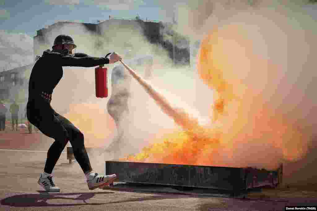 An competitor uses a fire extinguisher as he takes part in a relay event during the Fire and Rescue Championship held by the Russian Emergencies Ministry at the Lokomotiv Stadium in Yekaterinburg on July 25.&nbsp;