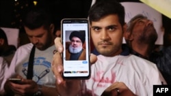 Një burrë tregon një foto të Hassan Nasrallah, sekretarit të përgjithshëm të Hezbollahut, ndërsa njerëzit demonstrojnë kundër Izraelit dhe sulmit në Liban, në Teheran, më 28 shtator.