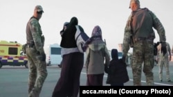 Kazakh military personnel escort a Kazakh family as they are repatriated from Syria during Operation Zhusan. The Kazakh government returned nearly 600 of its citizens in the operation, which took place in three stages between January and May 2019.