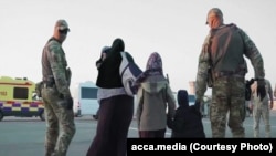 Kazakh military personnel escort a family as they are repatriated from Syria during Operation Zhusan in 2019.