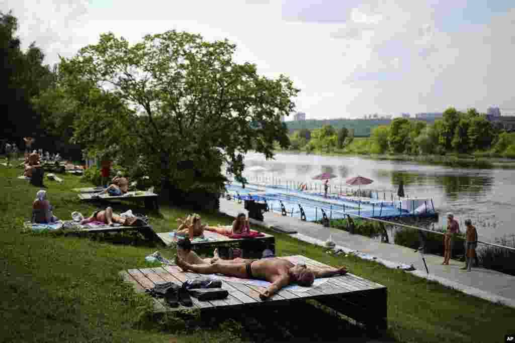 Russians sunbathe on a bank of the Moskva River during a hot day in Moscow's Fili Park.