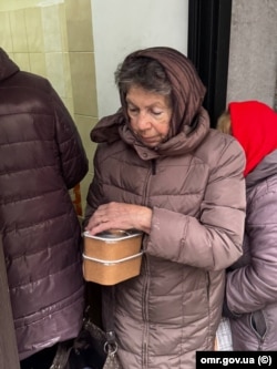 Жінка в Одесі з гарячою їжею, приготовленою в автономному поїзді-кухні від «Укрзалізниці» та Фонду Говарда Баффета. У перші дні блекауту готували 7 тисяч порцій щодоби, 15 грудня 2025 року