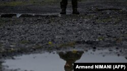 Un militar NATO oglindit într-o băltoacă la granița dintre Kosovo și Serbia, în timp ce sîrbii îndepărtau camioanele și automobilele care blocau frontiera kosovară, Jarinje, 2 octombrie 2021.