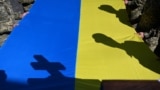 Ukrainian soldiers hold the national flag over the coffin of Volodymyr Pugolovko during his funeral at the Lychakiv Military Cemetery in Lviv.