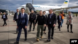 Președintele ucrainean Volodimir Zelenski (centru) este întâmpinat de ambasadorul elvețian în Ucraina, Felix Baumann (stânga) și de șeful adjunct al protocolului elvețian, Manuel Irman (dreapta), la sosirea sa pe aeroportul din Zurich, la 14 iunie, înainte de summit.