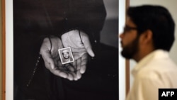  A visitor looks at a photograph showing a relative holding the portrait of a Pakistani prisoner under detention at the time by the U.S. at a prison in Afghanistan, during an exhibition in Islamabad in 2013.