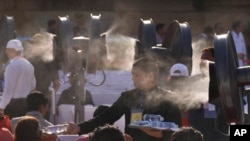 کارگری در حال توزیع بطری‌های آب در میان مهمانان یک مراسم دولتی